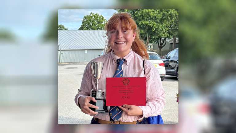 Kate Oakes with her latest award - a young woman holds a trophy and certificate